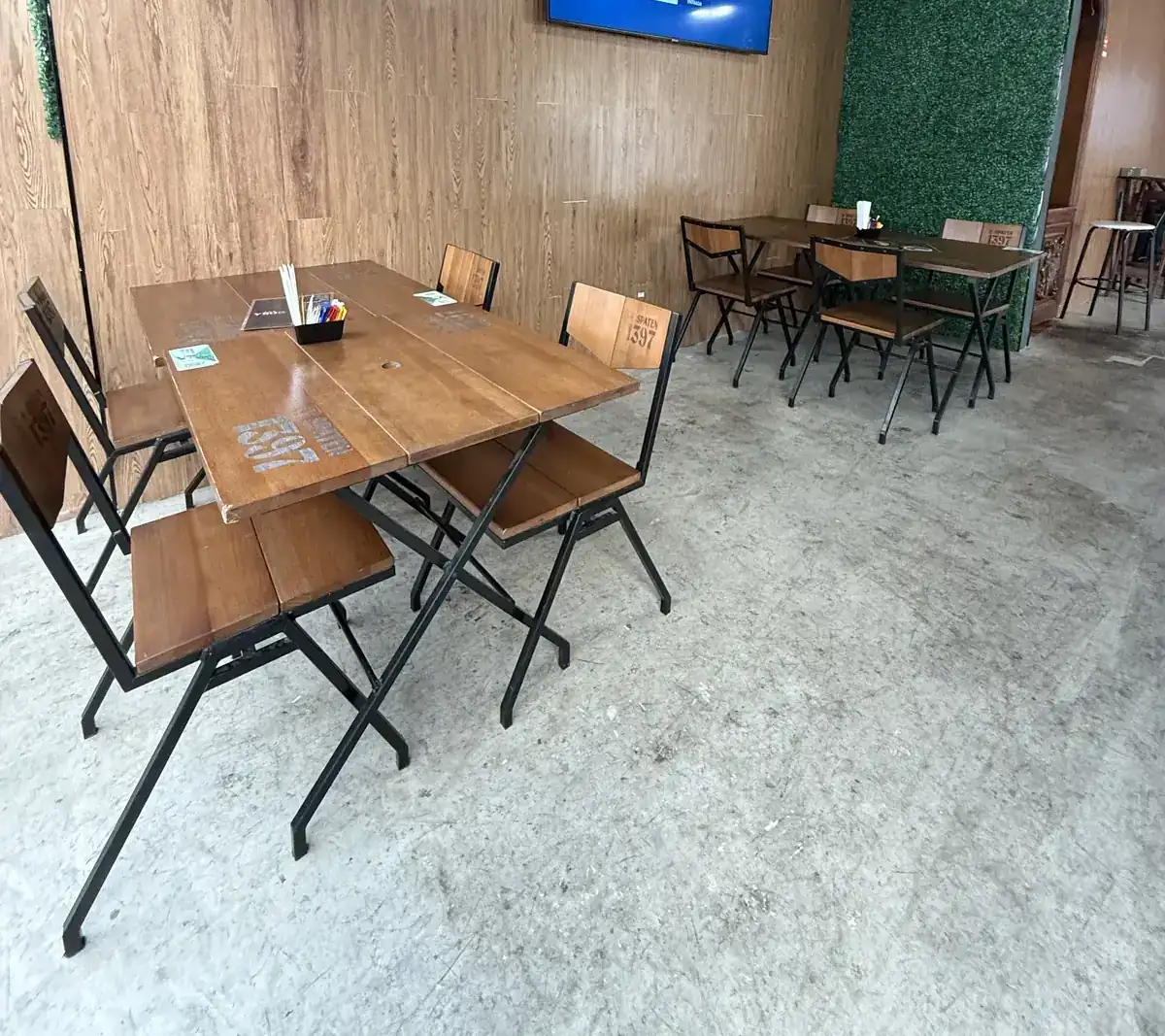 Ambiente interno do Zora Bar com TV na parede de madeira ripada