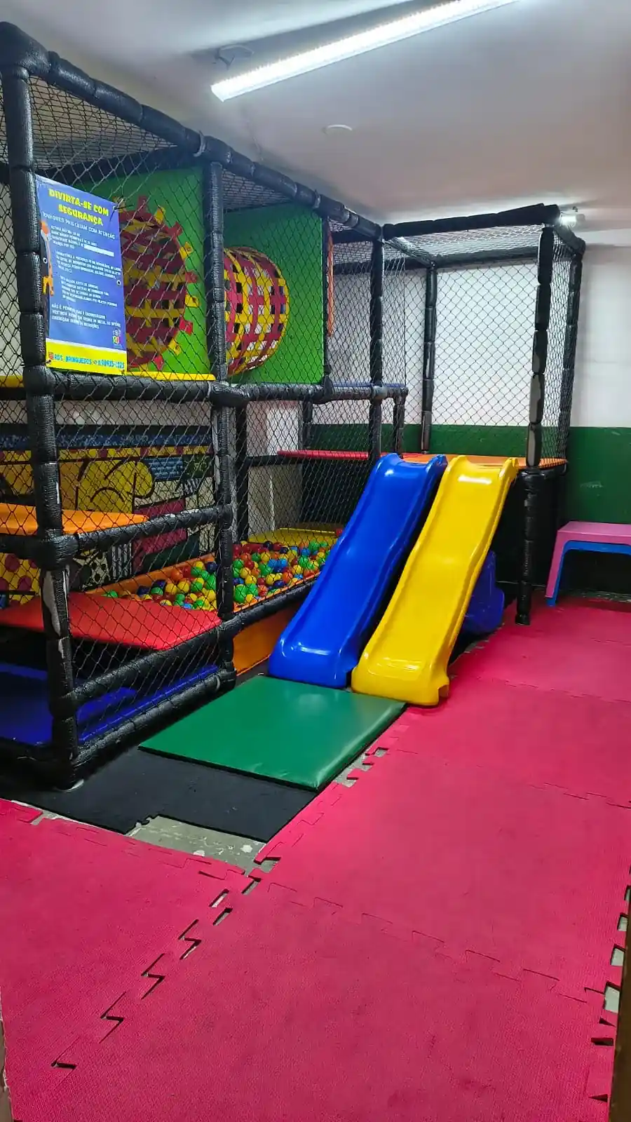 Espaço kids do Zora Bar em Santos, com brinquedão de rede, piscina de bolinhas e dois escorregadores