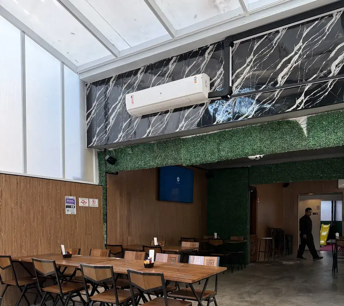 Mesas do salão interno do Zora Bar junto ao painel de madeira