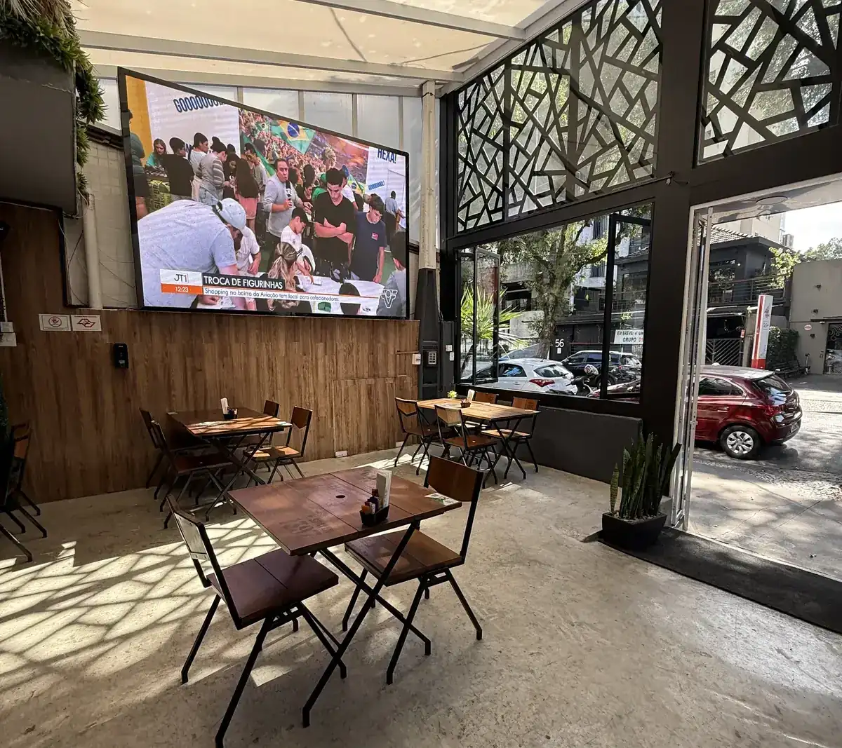 Mesas do Zora Bar voltadas para o telão durante transmissão de futebol