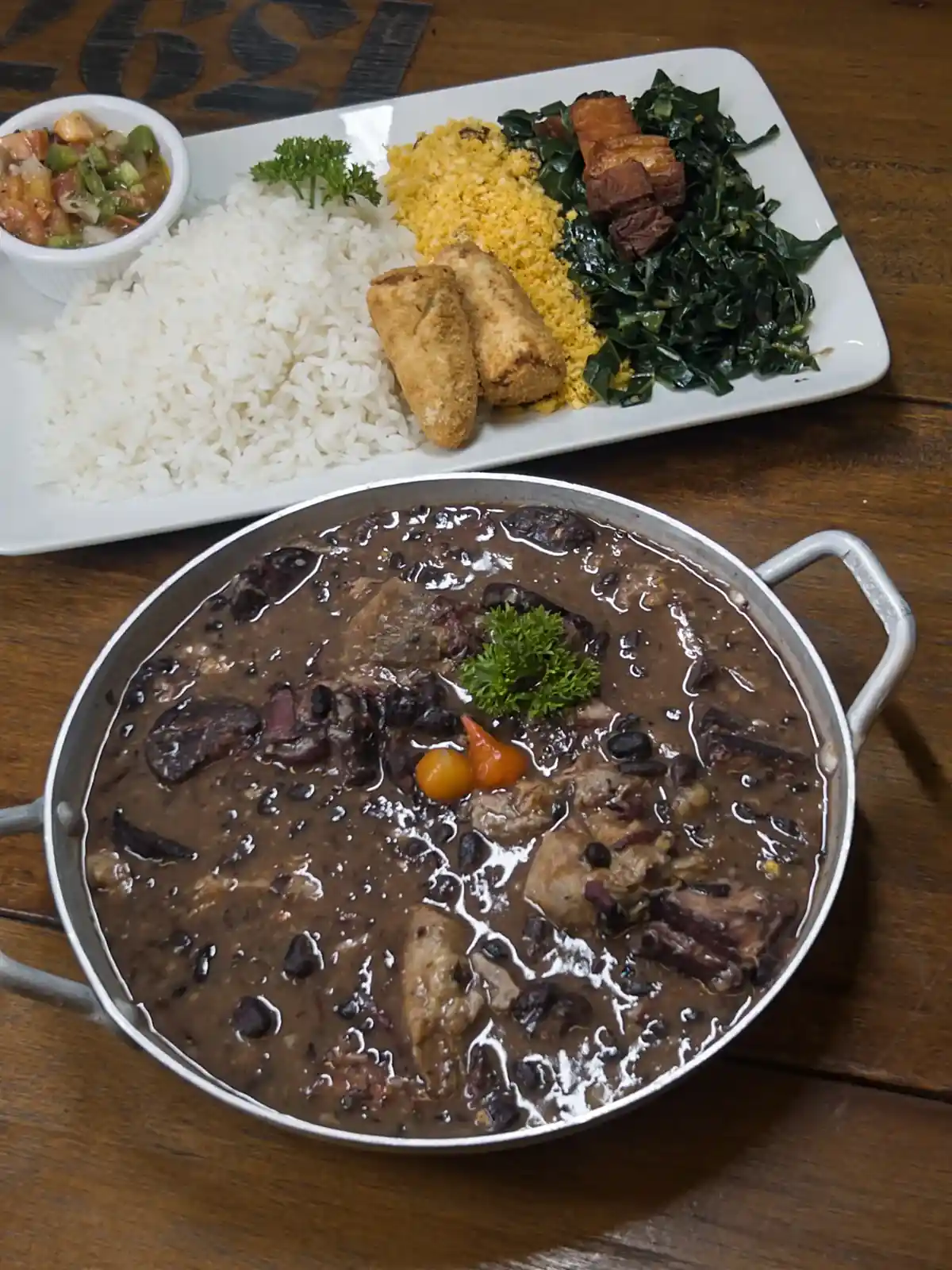 Feijoada completa do Zora Bar: panela com arroz, couve, farofa, torresmo e vinagrete
