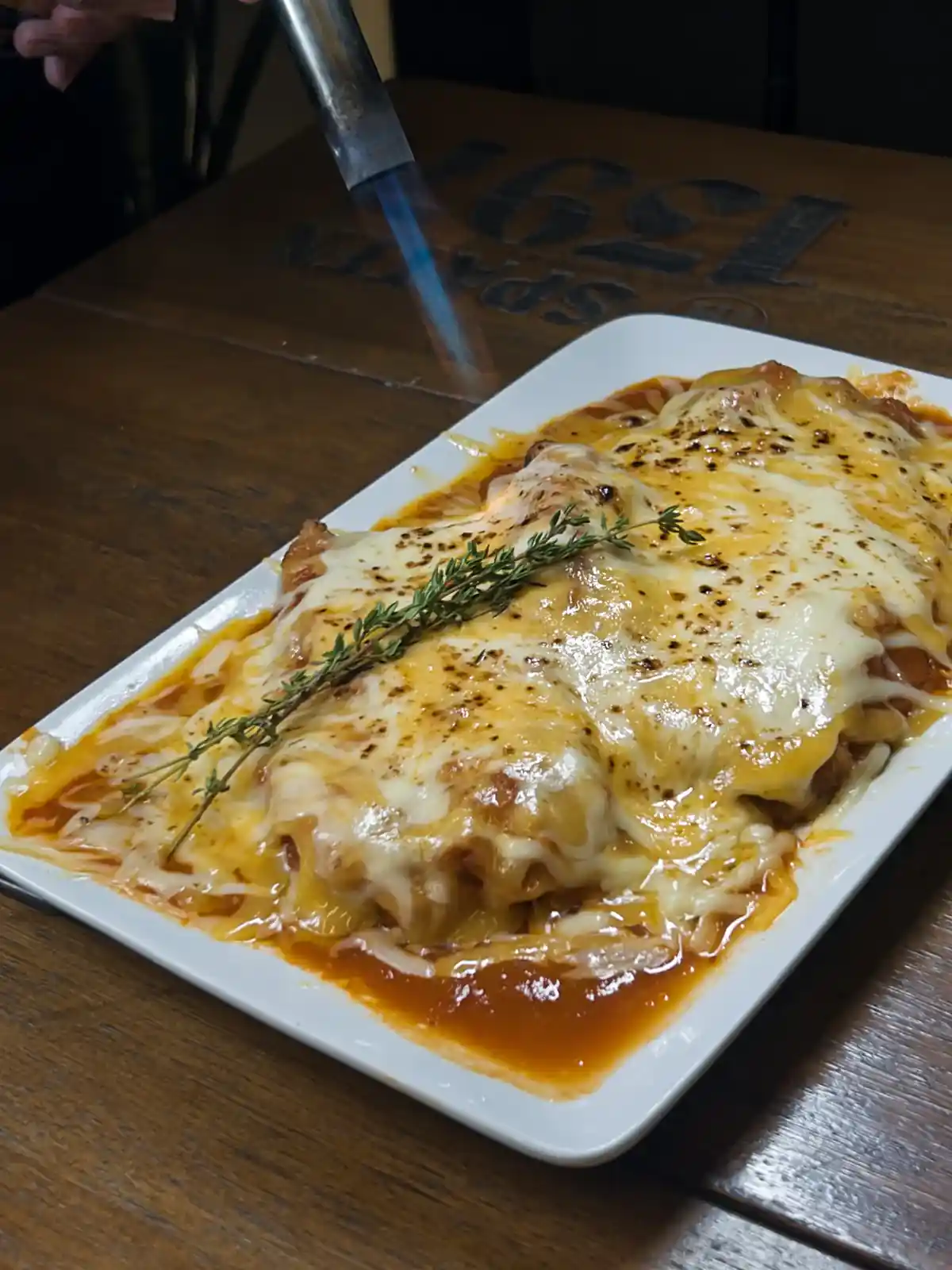 Parmegiana do Zora Bar com o queijo sendo gratinado no maçarico